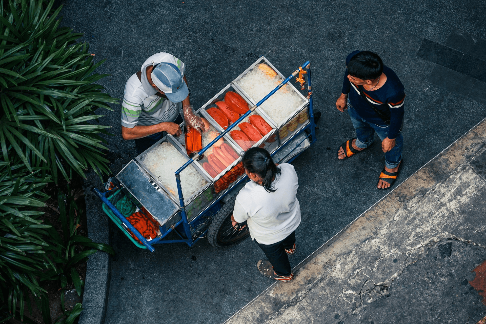 Birdseye view of Asian fish street food cart, with two customers waiting.